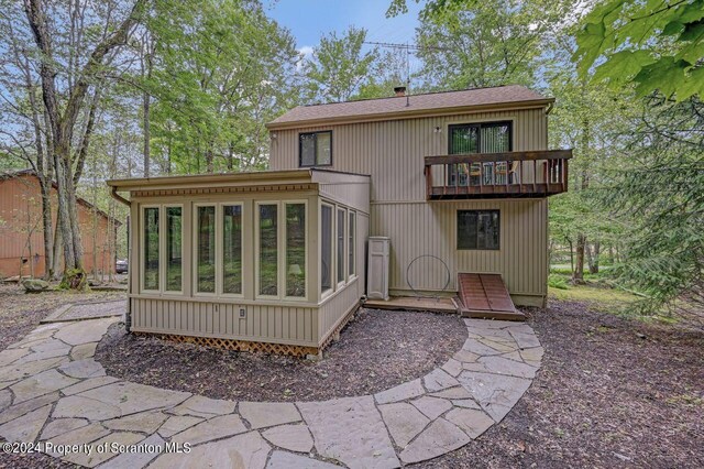 rear view of house featuring a balcony and a sunroom