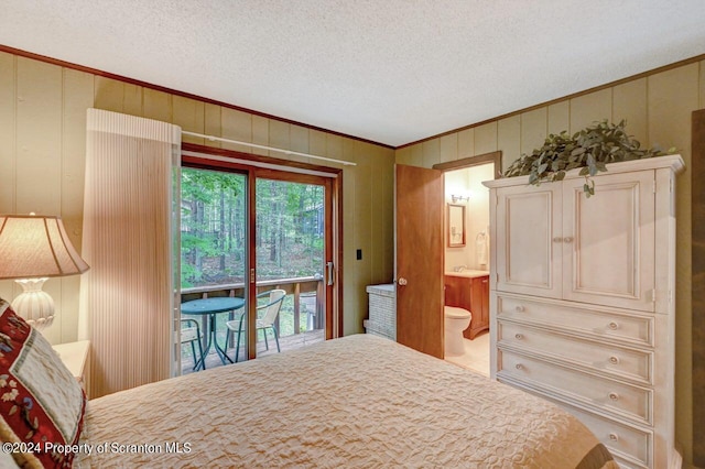 bedroom featuring a textured ceiling, access to outside, ensuite bath, and wooden walls