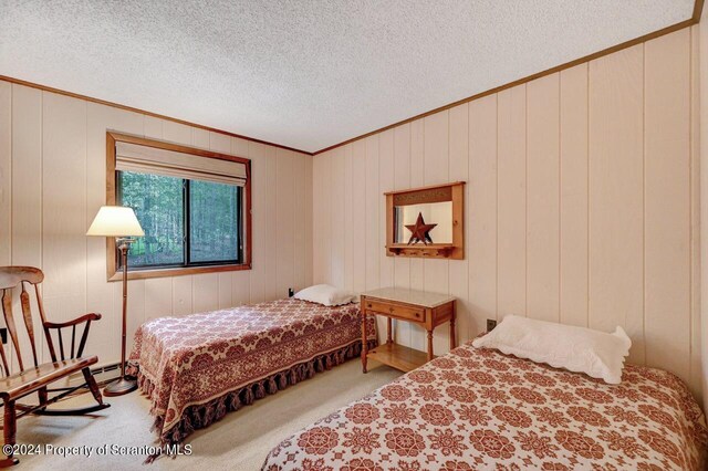 bedroom with carpet flooring, a textured ceiling, and wood walls