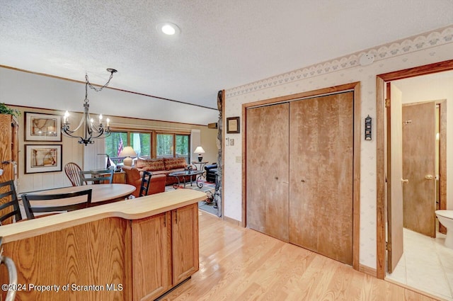 kitchen featuring a notable chandelier, decorative light fixtures, a textured ceiling, and light hardwood / wood-style flooring