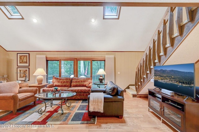 living room featuring light wood-type flooring, lofted ceiling with skylight, and wooden walls