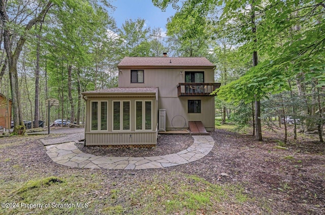 rear view of house featuring a balcony and a sunroom