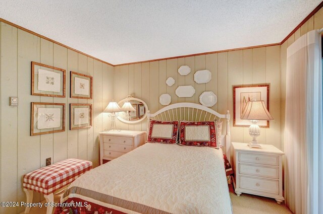 carpeted bedroom with wood walls, a textured ceiling, and ornamental molding