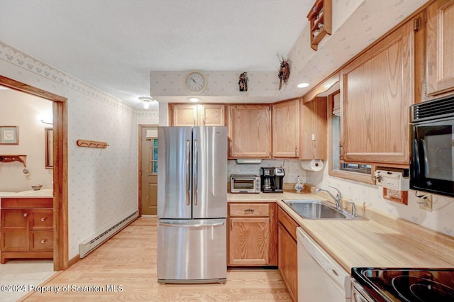 kitchen featuring white dishwasher, a baseboard heating unit, sink, light hardwood / wood-style floors, and stainless steel refrigerator