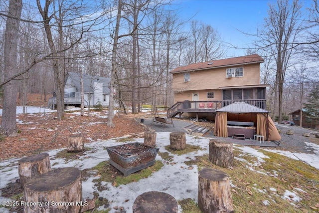 back of property with an outdoor fire pit, a sunroom, and a wooden deck