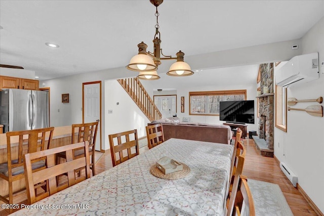 dining area with light wood-style flooring, recessed lighting, a baseboard heating unit, an AC wall unit, and stairway