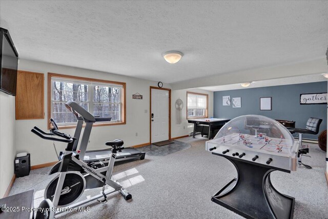 exercise room with a baseboard radiator, carpet, baseboards, and a textured ceiling