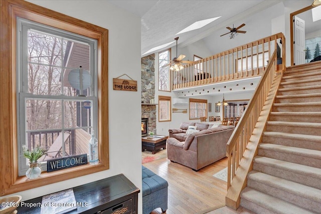 living area with a skylight, stairs, a wealth of natural light, and wood finished floors