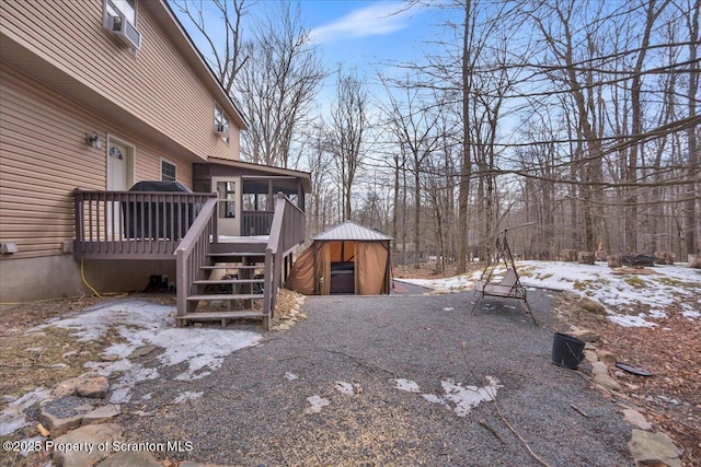 snowy yard with stairway, a sunroom, an outdoor structure, and a deck