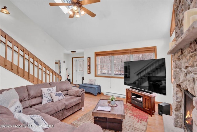 living room featuring ceiling fan, high vaulted ceiling, a baseboard radiator, wood finished floors, and stairway