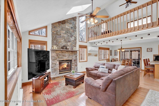 living room with ceiling fan, light wood-type flooring, a fireplace, and a wealth of natural light