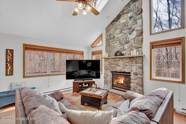 living area with a fireplace, a baseboard radiator, wood finished floors, and a healthy amount of sunlight