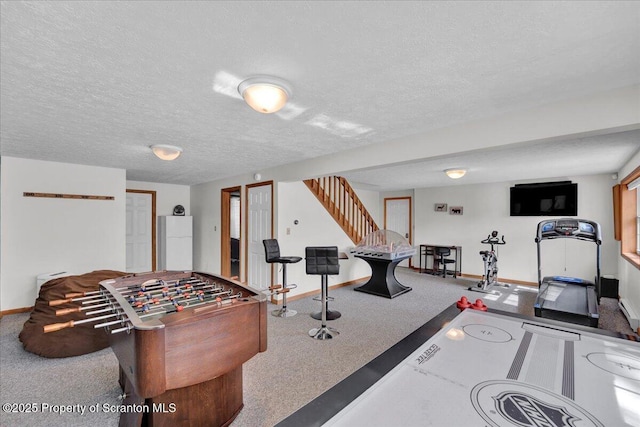 recreation room featuring a textured ceiling, carpet, and baseboards