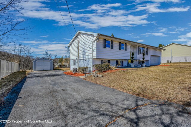 view of front of home with aphalt driveway, an outbuilding, a front yard, and fence