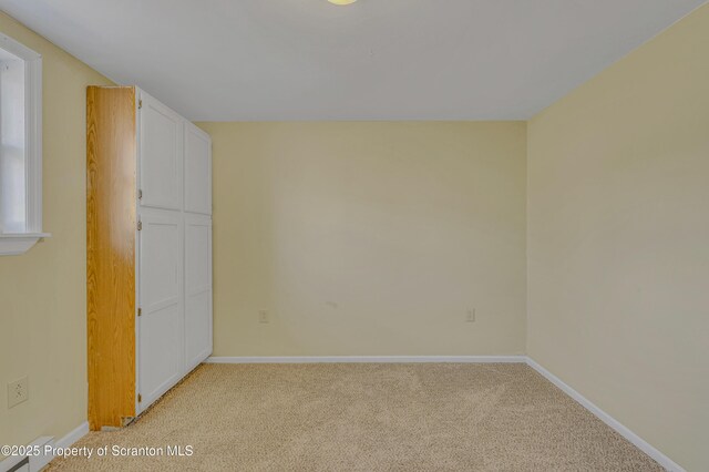 spare room with baseboards and light carpet