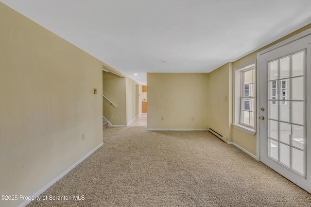 carpeted empty room with stairway, a baseboard heating unit, and baseboards