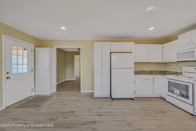 kitchen with light wood finished floors, white cabinets, white appliances, and baseboards