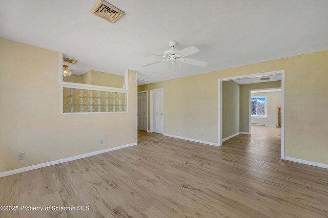 spare room featuring visible vents, baseboards, wood finished floors, and a ceiling fan