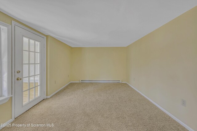 carpeted spare room with a baseboard heating unit and baseboards