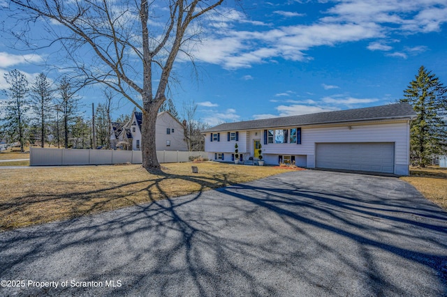 split foyer home with driveway, a front lawn, a garage, and fence