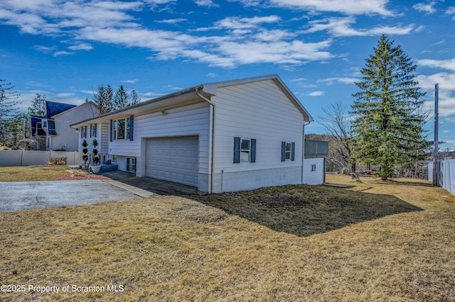 view of side of property with a lawn, an attached garage, driveway, and fence