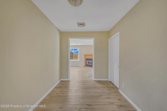 hall featuring light wood-style floors, visible vents, and baseboards