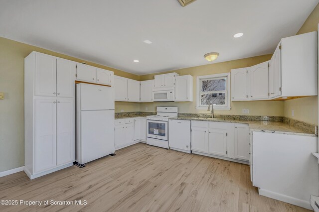 kitchen featuring white appliances, light wood finished floors, a sink, white cabinets, and baseboard heating