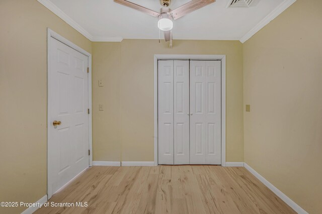 unfurnished bedroom featuring visible vents, a closet, crown molding, light wood finished floors, and baseboards