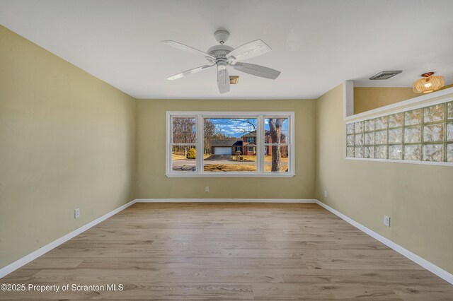 spare room with visible vents, a ceiling fan, baseboards, and wood finished floors