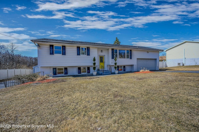 raised ranch featuring a garage, a front yard, and fence