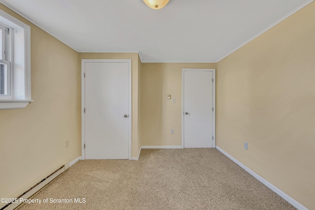 carpeted spare room featuring crown molding, baseboards, and a baseboard radiator