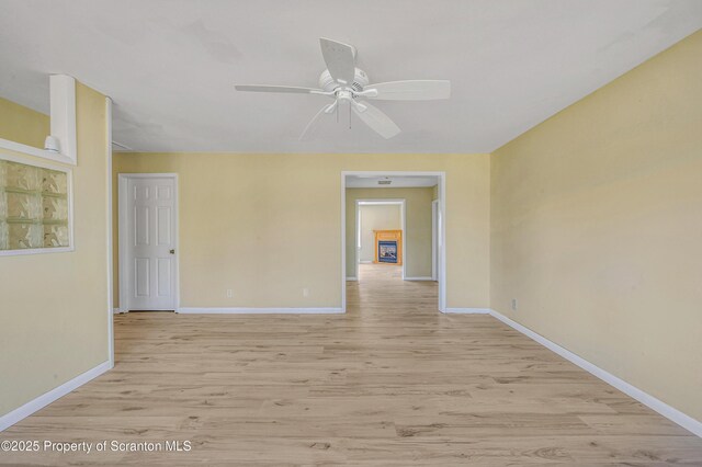 empty room with ceiling fan, baseboards, and light wood-style flooring