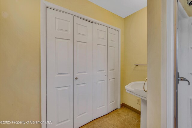 bathroom featuring tile patterned flooring, baseboards, and a closet