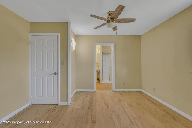 unfurnished bedroom with ensuite bathroom, baseboards, light wood-style flooring, and a ceiling fan