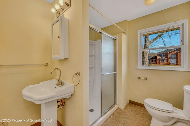 full bathroom featuring tile patterned floors, a shower stall, toilet, and baseboards