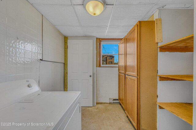 clothes washing area with tile walls, washer / clothes dryer, and cabinet space