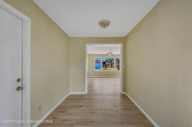 corridor featuring light wood-type flooring and baseboards