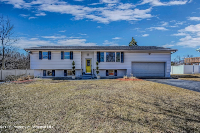 split foyer home featuring a front lawn, entry steps, aphalt driveway, fence, and an attached garage