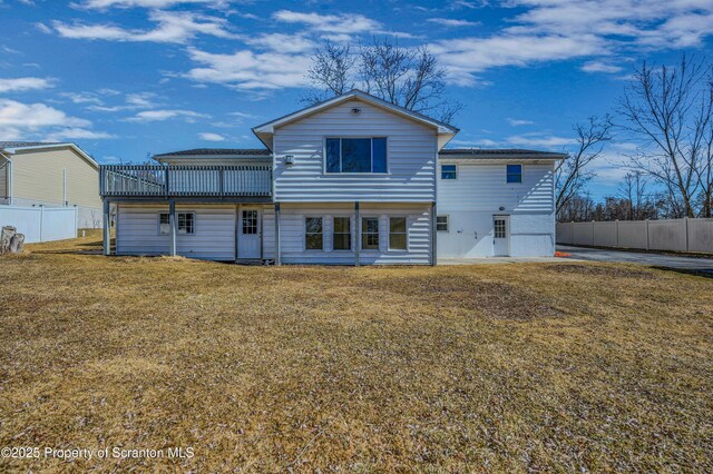 rear view of property featuring a yard and fence