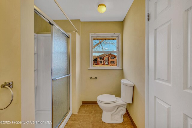 bathroom with baseboards, toilet, a stall shower, and tile patterned flooring