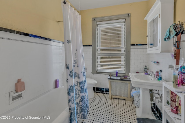 bathroom with toilet, tile walls, and shower / bathtub combination with curtain