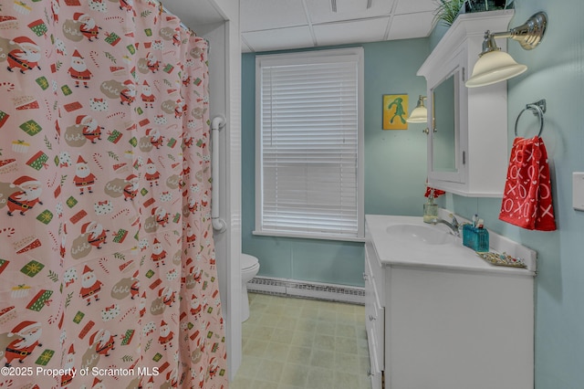 bathroom with toilet, a shower with shower curtain, a baseboard radiator, a drop ceiling, and vanity