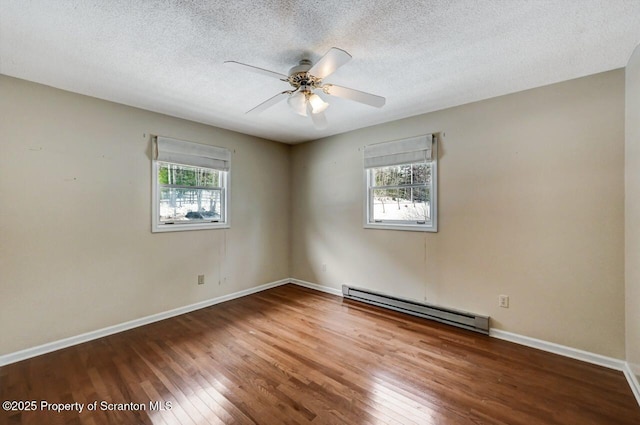 empty room with wood-type flooring, a baseboard radiator, a textured ceiling, and a wealth of natural light