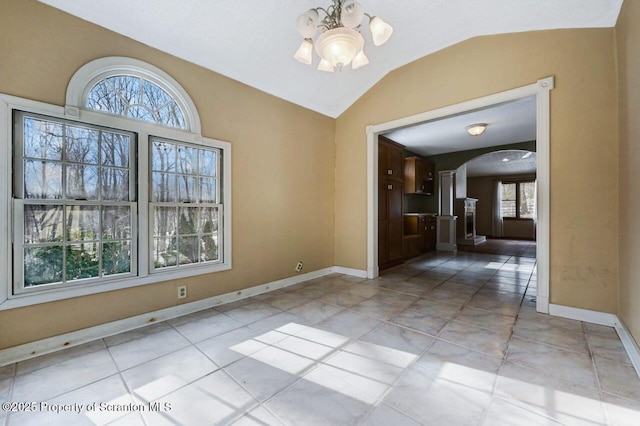 unfurnished dining area featuring lofted ceiling, light tile patterned flooring, a notable chandelier, and ornate columns