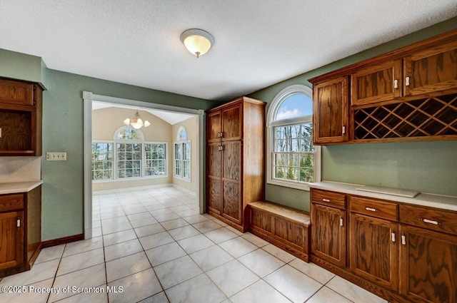 kitchen with lofted ceiling, an inviting chandelier, light tile patterned floors, and a textured ceiling