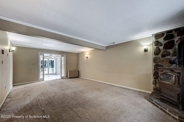 unfurnished living room featuring a textured ceiling, light colored carpet, crown molding, and a wood stove