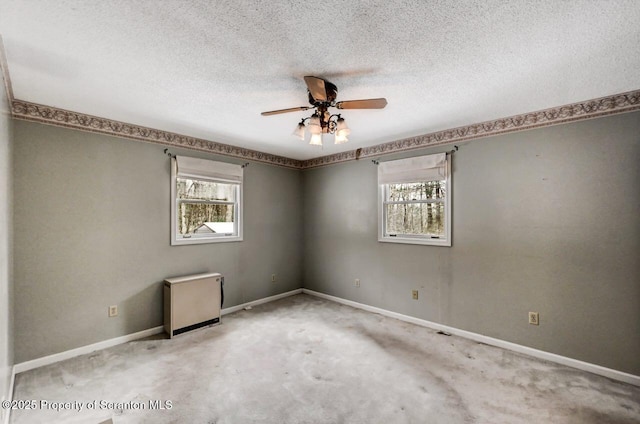 carpeted empty room featuring a textured ceiling, ceiling fan, and a healthy amount of sunlight