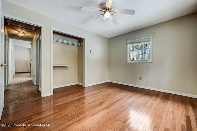 unfurnished bedroom featuring a closet, a textured ceiling, ceiling fan, and wood-type flooring