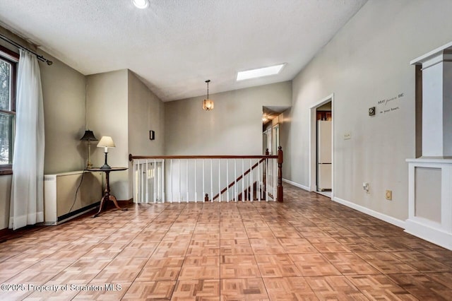 spare room with parquet flooring, a textured ceiling, and lofted ceiling with skylight