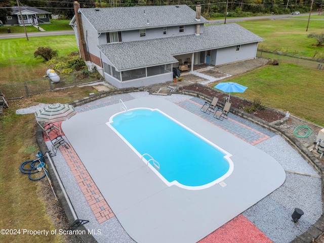 view of pool with a patio area, a sunroom, and a yard